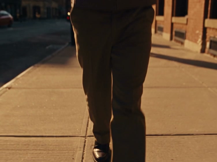 One continuous 12-second take with no cuts. The camera is the only thing that moves through the frozen moment; the world freezes, not the camera. Photoreal fashion film shot on 35mm.

0-2s: Start low on the shoes of a man walking along a sunny city street. The camera cranes smoothly up his body to reveal him in medium shot: he wears glasses with the supplied logo on the frame, holds a flip phone to his ear and carries a takeaway coffee cup in his other hand. The logo is also on the coffee cup and on the flip phone.

2-4s: The camera tracks backward ahead of him at his walking pace, keeping him in medium shot, as a passer-by walking a labrador comes toward him from the other direction.

4-5s: Their elbows clip. He falls back off balance and lets go of the coffee cup and the flip phone, and the glasses fly off his face. The cup tips and one edge of its lid pops up at the top.

5-6s: Time almost stops. The camera pulls out to a wide view of the frozen accident, every object hanging in the air: man, passer-by, dog, cup, phone and glasses.

6-7s: Bullet time. The camera travels through the frozen scene to the glasses and orbits them in macro, with shallow focus, showing the logo on the frame.

7-8s: The camera glides on to the tilted coffee cup. A thin stream of coffee escapes from the top through the gap where the lid has popped up. The bottom of the cup stays sealed and dry. The logo is visible on the cup.

8-10s: The camera moves on to the open flip phone, its screen clearly reading "BOSS", with the logo on its body.

10-12s: The camera pulls back to the whole scene, then time snaps back to normal speed: the man lands and every object falls along its own natural path.

Look: warm amber tones, visible film grain, shallow macro focus on the close details. Sunny city street. The supplied logo is reproduced exactly as in the reference on the cup, the phone and the glasses frames, with no other readable text except "BOSS" on the phone screen.

Sound (audio on, no music): street ambience with traffic and distant voices, and the muffled sound of his phone call in the first seconds. While time is frozen, the sound drops to a low hum. When time snaps back, the clatter of everything landing: cup, phone and glasses hitting the pavement.