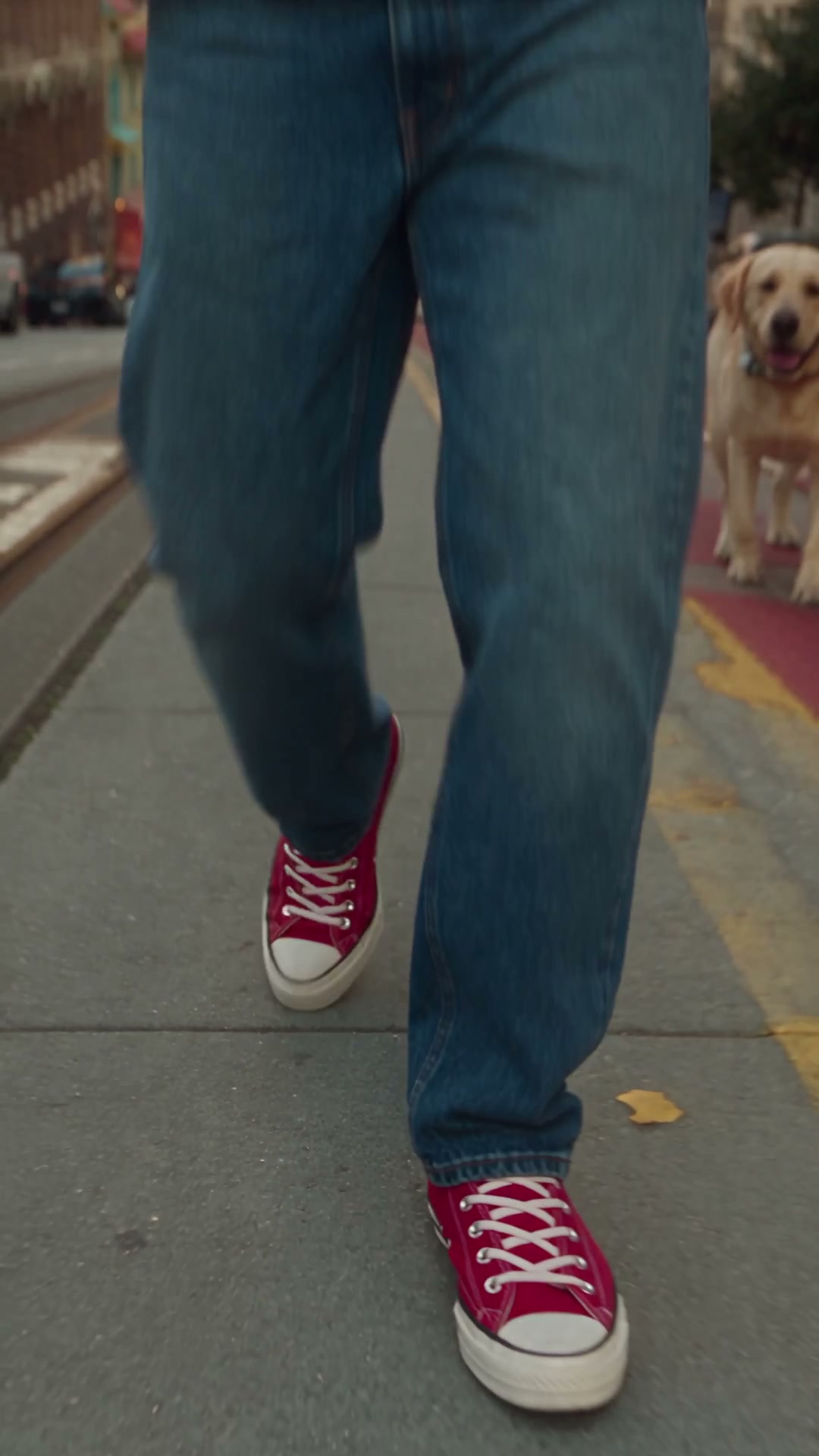 One continuous 12-second, ultra-photorealistic live-action shot, styled as a high-budget fashion campaign / cinematic music video with real actors, practical props, real high-speed photography. Environment: a San Francisco street inspired by the reference photo — steep sloped street with cable-car tracks, tall mixed-era skyscrapers, warm late-afternoon light — new camera angle, open pedestrian space for the walk and collision; pedestrians stay in pedestrian areas, vehicles in vehicle areas, realistic scale.

CRITICAL PHONE RULE: there is exactly ONE phone in this whole video: a compact early-2000s silver-gray OPEN CLAMSHELL FLIP PHONE — two hinged rectangular halves, small illuminated display and speaker on top, physical numeric keypad and microphone below, visible central hinge, already open. This exact flip phone is in the protagonist's RIGHT HAND from the very first frame, held to the right ear during a call, and it is this SAME phone that later releases from the hand. No modern smartphone or touchscreen phone ever appears, in this hand or anywhere, at any camera distance. Wide, medium, and macro shots all show this one identical device.

CENTRAL CONCEPT: a dramatic bullet-time accident. At the collision, objects get one short realistic release impulse each, then time drops to about 2-3% speed. Released objects become nearly stationary fixed points in 3D world space while only the CAMERA moves through the frozen moment to inspect them — objects never fly toward the lens or self-enlarge; only reduced camera distance creates each close-up. Real-world physics, causality and spatial continuity are critical.

EXACT COUNTS: one protagonist, one secondary passer-by, one Labrador on one leash, one MITO Clubmaster sunglasses (hero object), one coffee cup with plastic lid, one silver-gray open flip phone as above. No duplicate or different props anywhere.

HAND OWNERSHIP before collision: RIGHT HAND holds the same open flip phone (small MITO logo) to the right ear, mid call, natural subtle lip/jaw movement. LEFT HAND holds the paper coffee cup (small MITO logo), lid attached, coffee inside. The MITO Clubmaster sunglasses are worn on the face.

0.0-2.0s REVEAL: extreme low close-up on the protagonist's red high-top Converse walking; one continuous smooth crane-up plus gentle backward tracking reveals in order: red Converse -> relaxed blue jeans -> white "I ❤️ SF" t-shirt -> torso -> MITO Clubmaster sunglasses on the face -> full protagonist, still on the same flip phone, coffee in left hand.

2.0-3.7s WALK: smooth frontal tracking continues; exactly one secondary person walking one Labrador on a leash approaches from the opposite direction (dog slightly ahead). They stay supporting elements. Identity, wardrobe, sunglasses, the same flip phone, and coffee stay fully stable — phone never changes shape or type.

3.7-4.4s COLLISION: the secondary person's elbow accidentally clips the protagonist's arm/torso — small, believable contact. The protagonist recoils backward. Three release events from this same collision: (1) the sunglasses get one short outward impulse and separate from the face, traveling only a short distance, never toward the camera; (2) the coffee cup leaves the left hand with a short outward/downward rotational impulse, tilts and rotates, and rotation plus liquid inertia pops one edge of the lid loose, opening a real gap through which coffee only then begins escaping, slow and restrained; (3) the SAME flip phone leaves the right hand with a short outward/upward impulse, keeping its exact design and open angle — the identical device held since frame one, never a different phone. The instant each object leaves, that hand is completely empty — nothing else ever appears in the right hand before or after that release. The protagonist's face and eyes are already complete under the sunglasses and are revealed normally once they separate: stable pupils, natural eyelids, correct gaze, symmetrical brow/nose/cheekbones. Hair keeps its shape with only subtle natural inertia.

4.4-5.2s FROZEN WORLD: time drops to ~2-3% speed. First hold a clear medium-wide view of the whole accident before any macro inspection — protagonist beginning to fall backward, both hands empty, sunglasses suspended a short distance from the face, coffee cup suspended lower toward the left-hand side with its partly detached lid and a small escaping stream, and the same open flip phone suspended on the opposite right-hand side. These become fixed world-space anchors; objects drift only microscopically and never approach the camera or grow in frame — the camera alone moves from here on.

5.2-6.8s HERO OBJECT: camera dollies toward the nearly stationary sunglasses, slows, holds, then a restrained 20-30 degree orbital parallax around them. Reveal the glossy black acetate, gold-tone hinge rivets, small "MITO" wordmark beside the rivet, real material thickness, edges, reflections, shallow depth of field, falling protagonist softly visible behind. Must read as a real product shot with a macro cinema lens, never CGI. Complete before moving on.

6.8-8.3s COFFEE: camera travels diagonally to the same cup, holds a macro close-up: same paper cup, lid partly detached along one edge, a thin irregular stream and a few droplets escaping through the real gap, natural surface tension and reflections — no explosion, no CGI splash. Small lateral parallax move, then leave.

8.3-9.8s PHONE: camera travels to the same suspended flip phone — the identical device since frame one, never a smartphone — first holding its complete silhouette with hinge and keypad to confirm it's the same device, then moving closer to the display for an extreme macro close-up where the illuminated screen reads "BOSS" with a small phone number beneath, real surface wear and reflections. The right hand stays empty in the background. The phone never becomes a smartphone or a different phone.

9.8-10.4s RECONSTRUCT: a fast, smooth backward dolly reveals the complete frozen accident again — protagonist still falling, both hands empty, the sunglasses, the cup with its droplets, and the same flip phone all still at their established positions, plus the secondary person and Labrador — nothing teleported, regenerated, or changed type.

10.4-12.0s PAYOFF: time snaps back to normal speed; gravity and momentum resume together. The protagonist completes the fall. The sunglasses continue from their position and land under their own momentum. The coffee cup continues, hits the ground, remaining coffee spills irregularly from the real opening/impact point. The same flip phone continues, strikes the ground, makes one small believable bounce. The three objects land at different plausible spots, not converging beside the protagonist. Camera tilts/drops to ground level for a low-angle finish connecting the fallen protagonist and scattered objects on the same street. Hard cut to end.

Every visible change needs a physical cause; nothing transforms just because the camera gets closer; no prop is duplicated or regenerated; the phone is one silver-gray flip phone from first frame to last, never a smartphone.